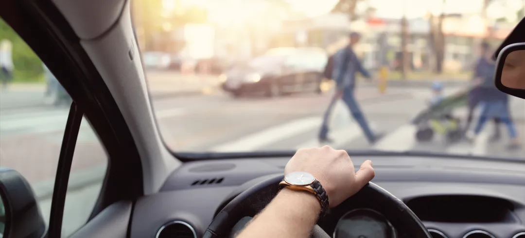 Persona conduciendo mientras cede el paso a peatones
