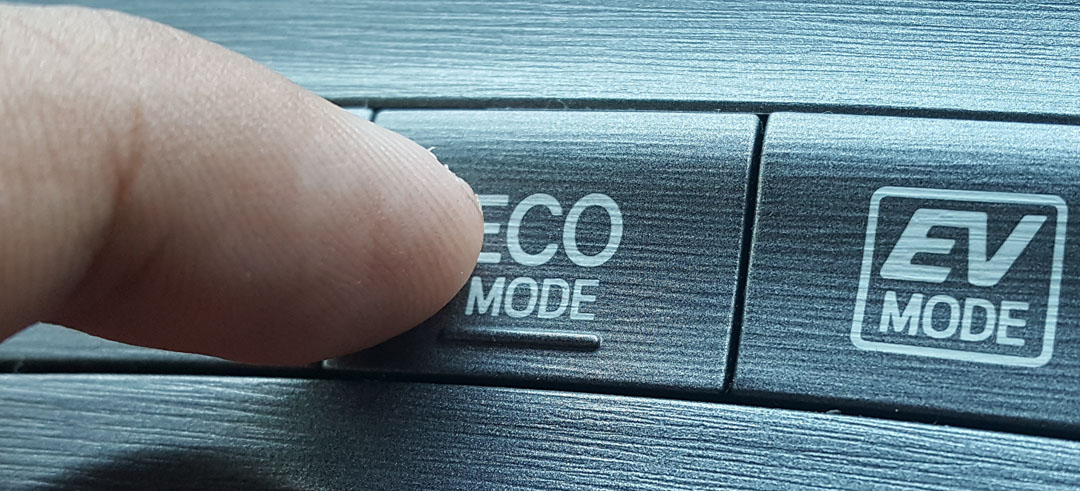 Persona apretando el botón de modo eco en un vehículo